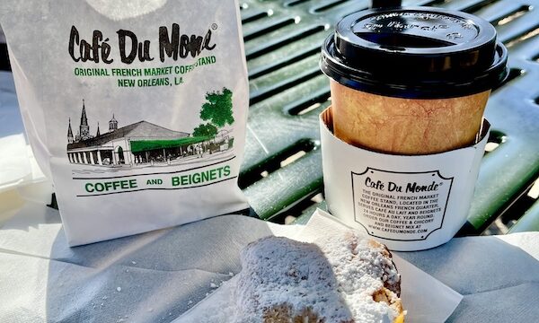 Café du Monde City Park NOLA coffee and beignet on an outdoor table.