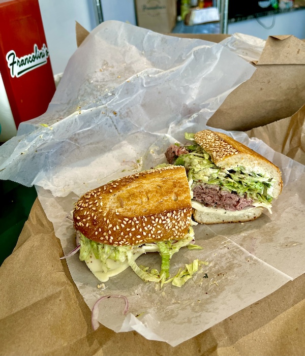 Francolini's Italian Deli NOLA seeded sub with roast beef and lettuce sitting on deli paper