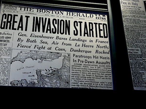 Newspaper headlines about the invasion of Normandy at the Torn roof exposed to the sky with WW2 planes seen flying overhead