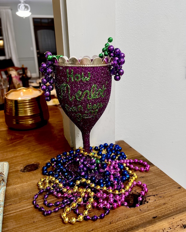 Mardi Gras State of Mind with a glitter covered wine glass surrounded by colored beads