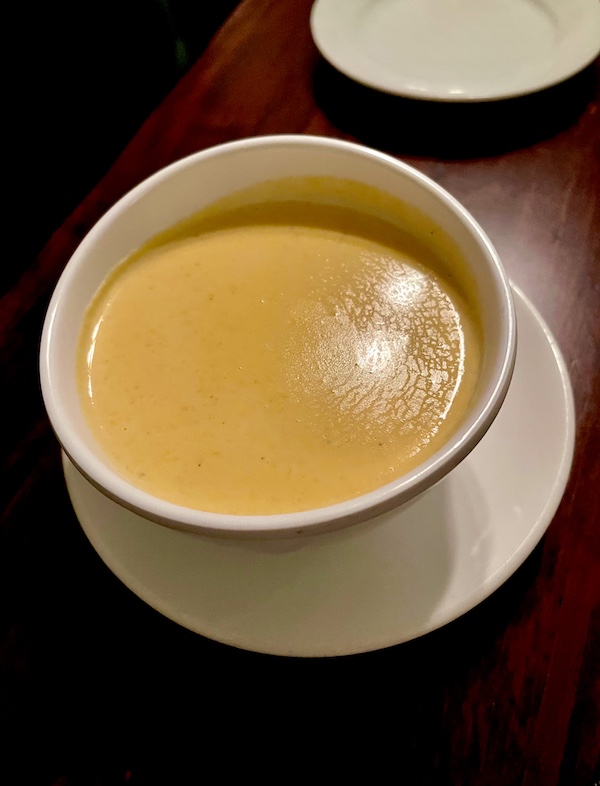 White soup cup of creamy orange soup put me in a Mardi Gras State of Mind