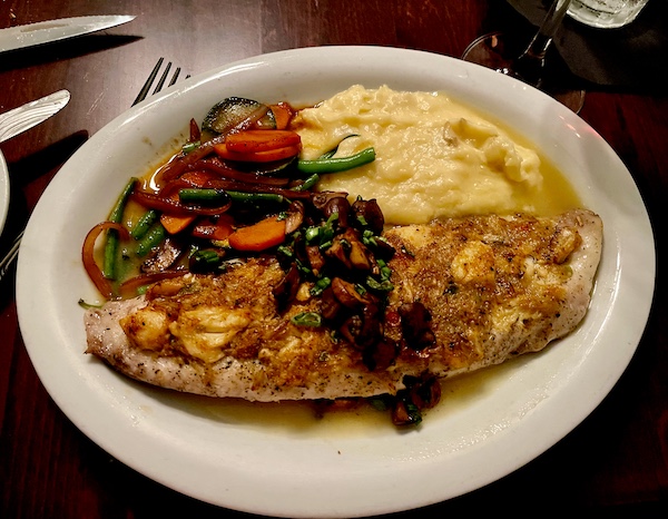 White plate topped with cooked whole filet of fish with sauce, mashed potatoes and mixed veg, put me in a Mardi Gras State of Mind
