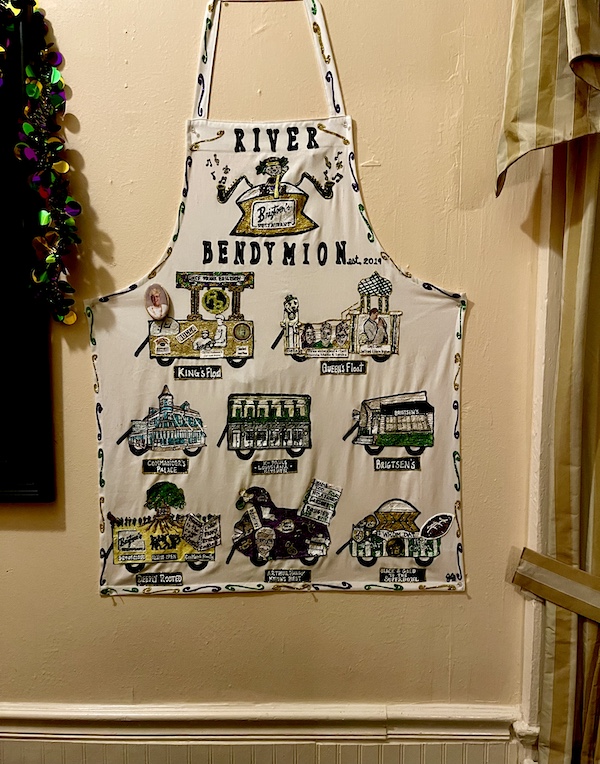 Mardi Grass decorated chef apron hanging on a beige wall