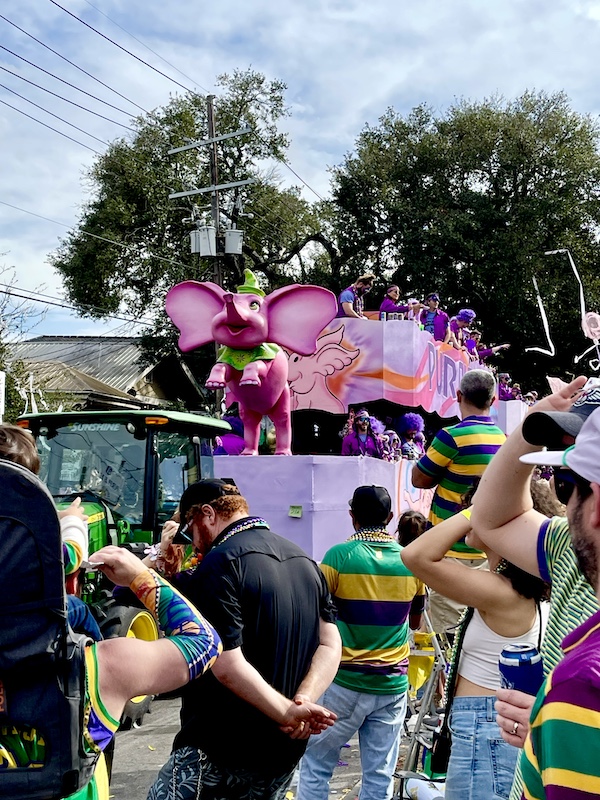 Our First Mardi Gras Parade with a pink and purple float with pink elephant on front.