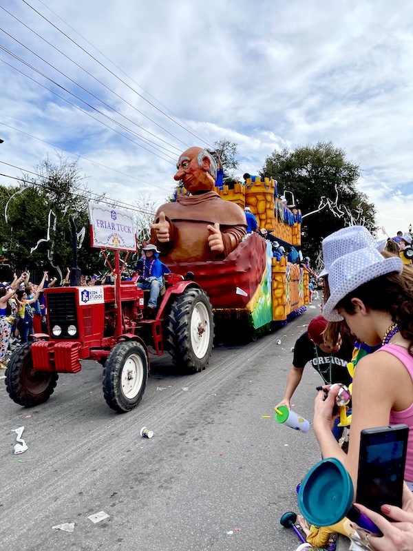 Huge Friar Tuck statue pulled by a red tractor at Our First Mardi Gras Parade