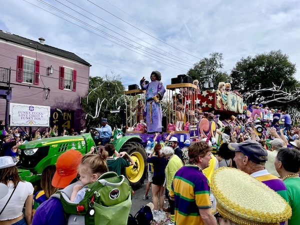 Wild and colorful float at Our First Mardi Gras Parade with lots of parade watchers