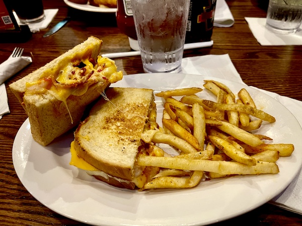 Fish City Grill Pearland TX grilled cheese and seafood sandwich with fries on a plate.