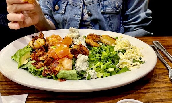 Fish City Grill Pearland TX large salad on an oval plate with shrimp, eggs and blue cheese.