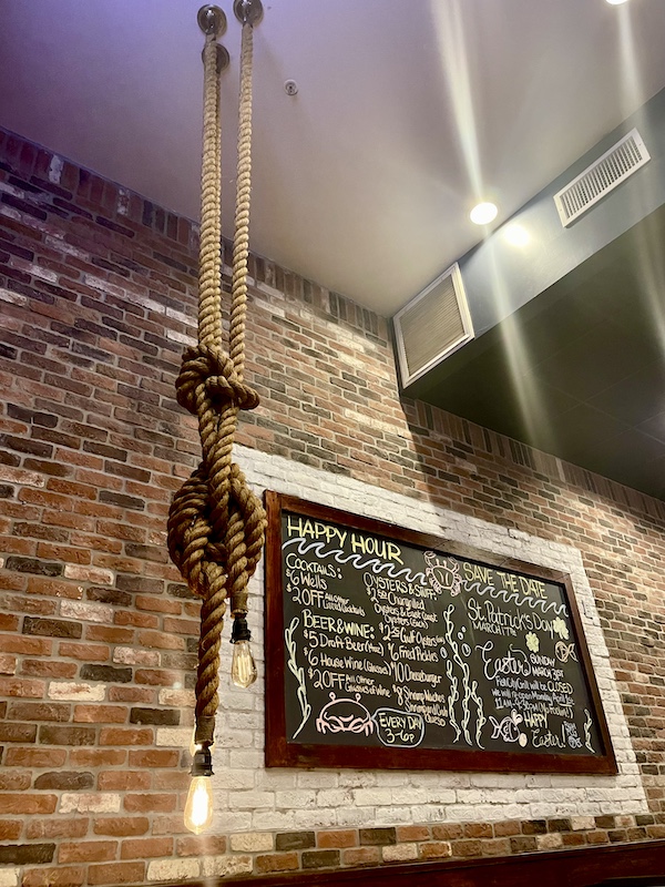 Fish City Grill Pearland TX chalkboard menu in front of a brick wall and a rope light fixture