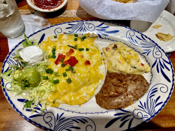 Blue patterned plate topped with a quesadilla, guacamole, sour cream, potatoes and beans at Abuelo's Mexican Restaurant Midland TX