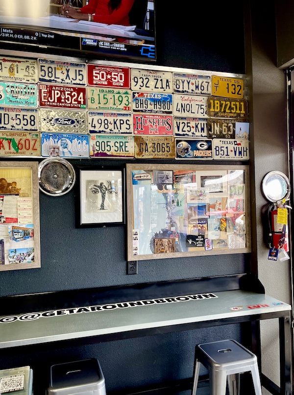 Old license plates from various states on a wall inside Get Around Brown BBQ Midland TX