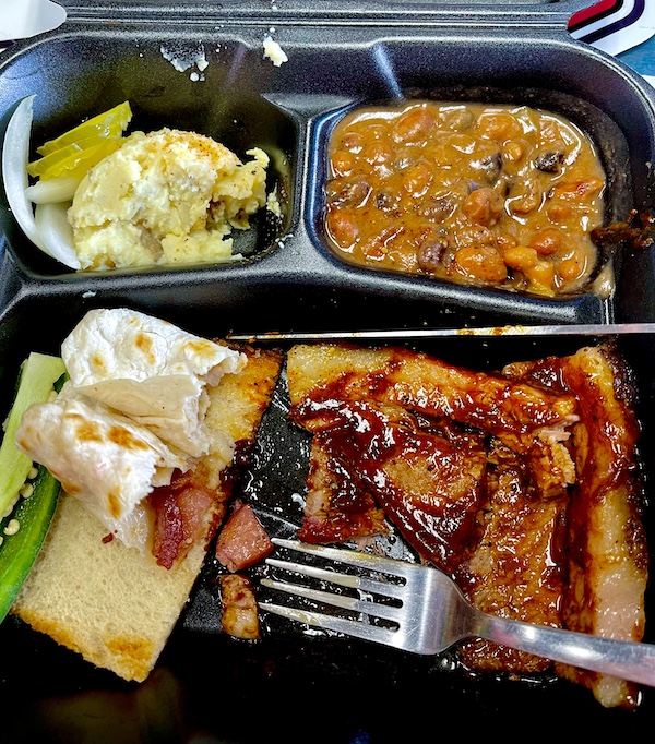 Divided tray holding slices of beef with BBQ sauce, toast, potato salad and baked beans with a fork at Get Around Brown BBQ Midland TX