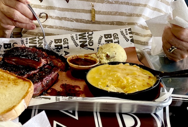 Tray holding bbq ribs, bowl of sauce, scoop of potato salad and cast iron skillet of mac and cheese at Get Around Brown BBQ Midland TX
