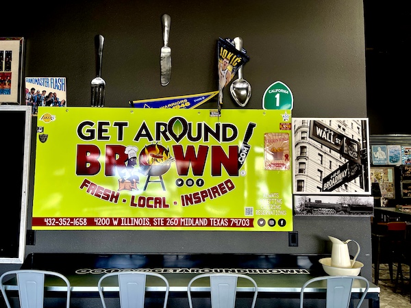 Lime green banner and giant flatware hanging on a wall at Get Around Brown BBQ Midland TX