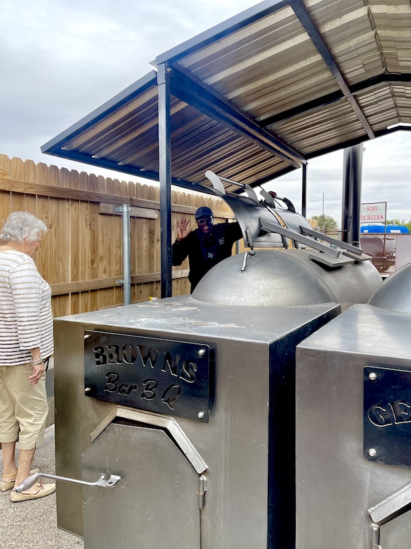 Chef standing it one of the two giant stainless steel smokers at Get Around Brown BBQ Midland TX