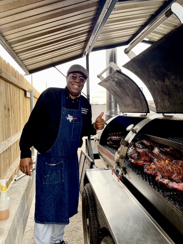 Chef standing at open smokers with meat cooking at Get Around Brown BBQ Midland TX