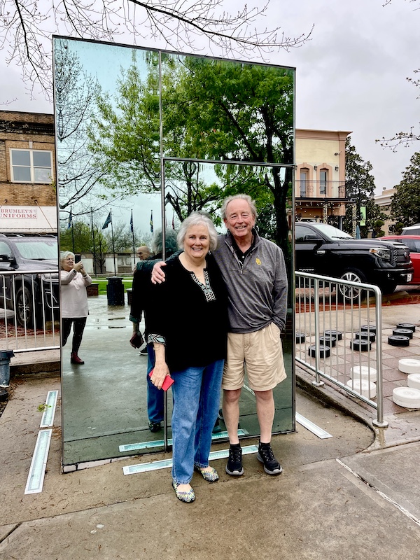 Man in shorts and woman in jeans in front of one of the Glass Bathrooms of Sulphur Springs TX