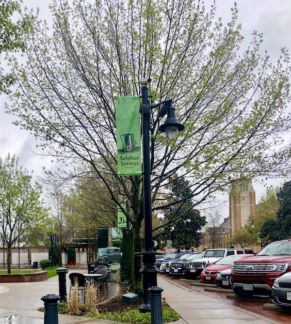 Green banner on a light post welcoming us to Sulphur Springs Texas