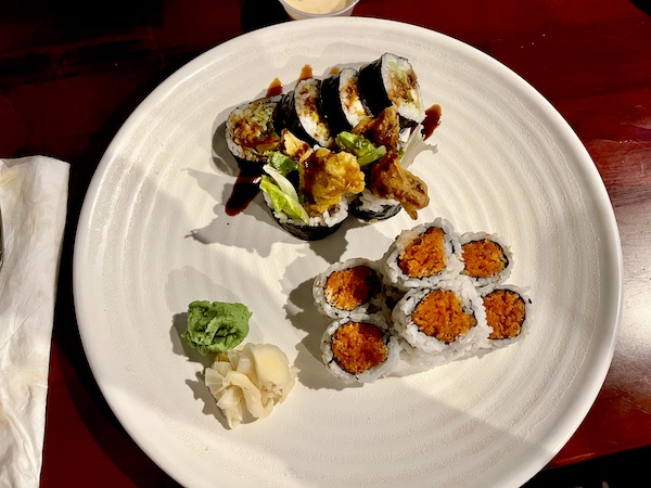 Round white plate topped with two different sushi rolls, wasabi and pickled ginger at Sakura Sushi Sulphur Springs TX