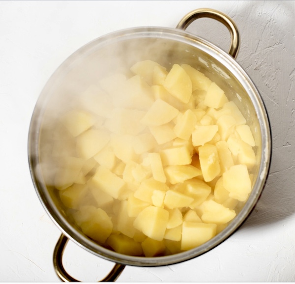 Cut potatoes in a pot of steaming water cooking for my Garlic Horseradish Mashed Potatoes recipe