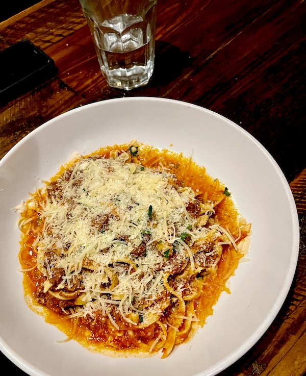 White pasta bowl filled with noodles, red meat sauce and grated cheese at Locale Neighborhood Italian Tucson