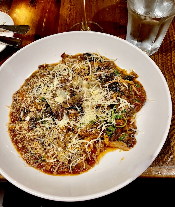 White pasta bowl filled with ribbon noodles and pork, mushroom ragu with grated cheese at Locale Neighborhood Italian Tucson