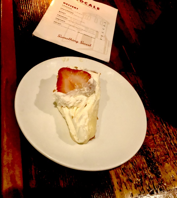 White dessert plate topped with wedge of frozen lemon pie with whipped cream and strawberry at Locale Neighborhood Italian Tucson