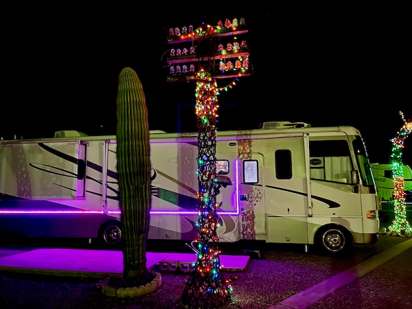 RV with pink lights next to cactus and tall sculpture with lots of colored lights during Our Visit to Quartzite Arizona