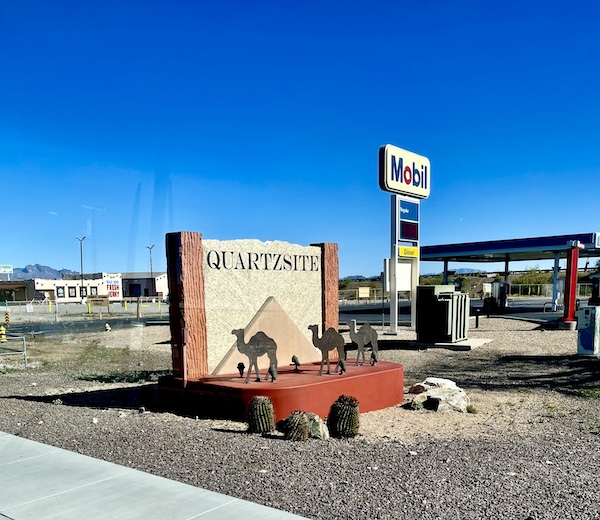 Wall welcoming you to Quartzite with camel statues, cactus and gas station seen on Our Visit to Quartzite Arizona