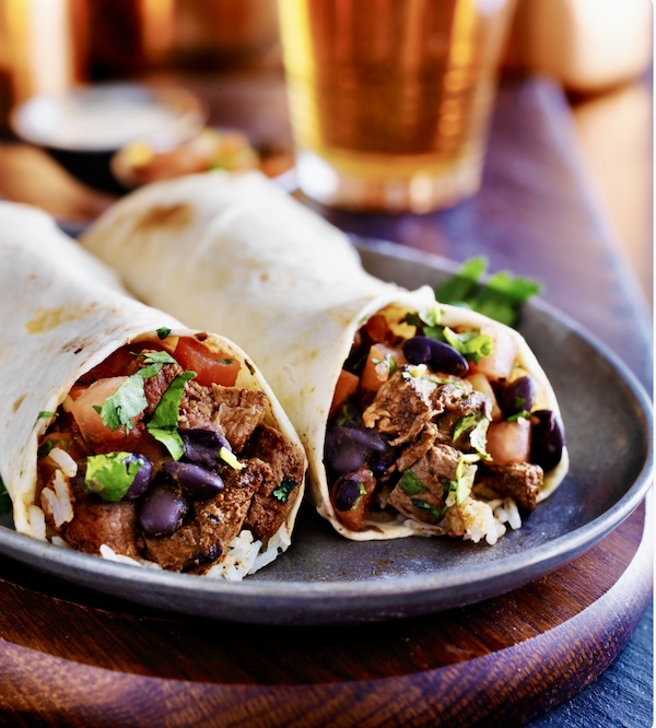 Plate topped with a meat and veggie burrito cut in half that's similar to the one from Kogi Food Truck in Pasadena CA