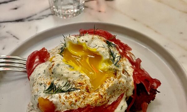 Plate topped with potato latke, smoked salmon, poached egg with runny yolk and pickled red onions at Moonlark's Dinette The Hoxton LA