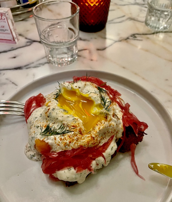 Plate topped with potato latke, smoked salmon, poached egg with runny yolk and pickled red onions at Moonlark's Dinette The Hoxton LA