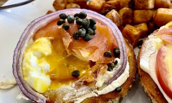 Eggs benedict with lox onion and capers showing one poached egg with yolk running out for Brunch at Scrambled Henderson NV