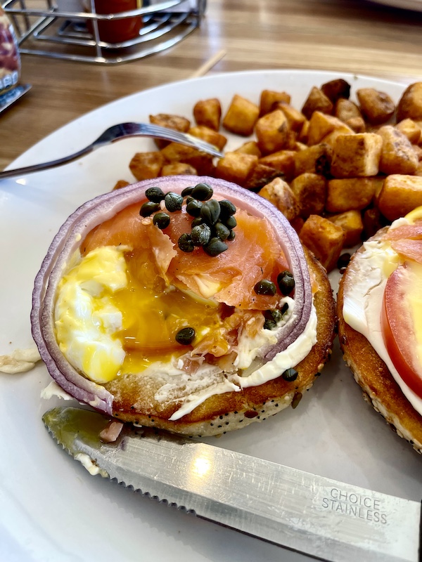 Eggs benedict with lox onion and capers showing one poached egg with yolk running out for Brunch at Scrambled Henderson NV