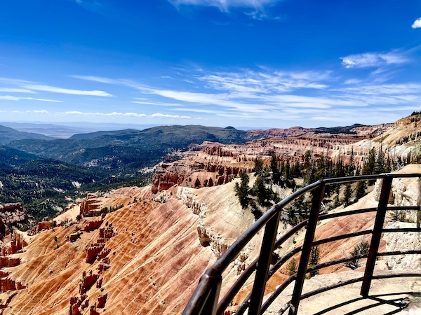 Pink and white striped canyon dotted with trees and more mountains in the distance at Cedar Breaks National Monument
