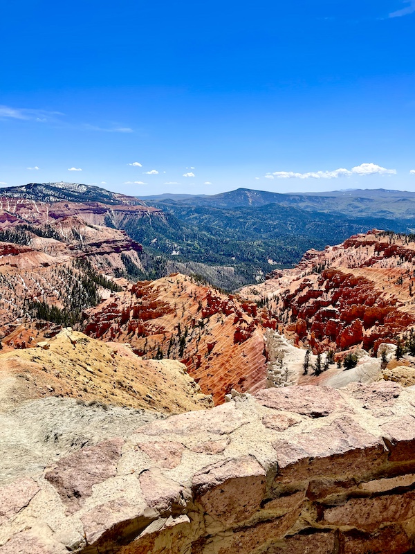 View of distant mountains and red rock formations in the foreground at Cedar Breaks National Monument