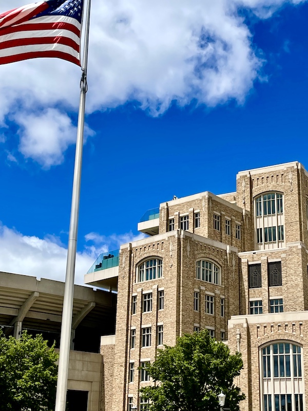 American flag on pole by football stadium for a Happy July 4th 2024!