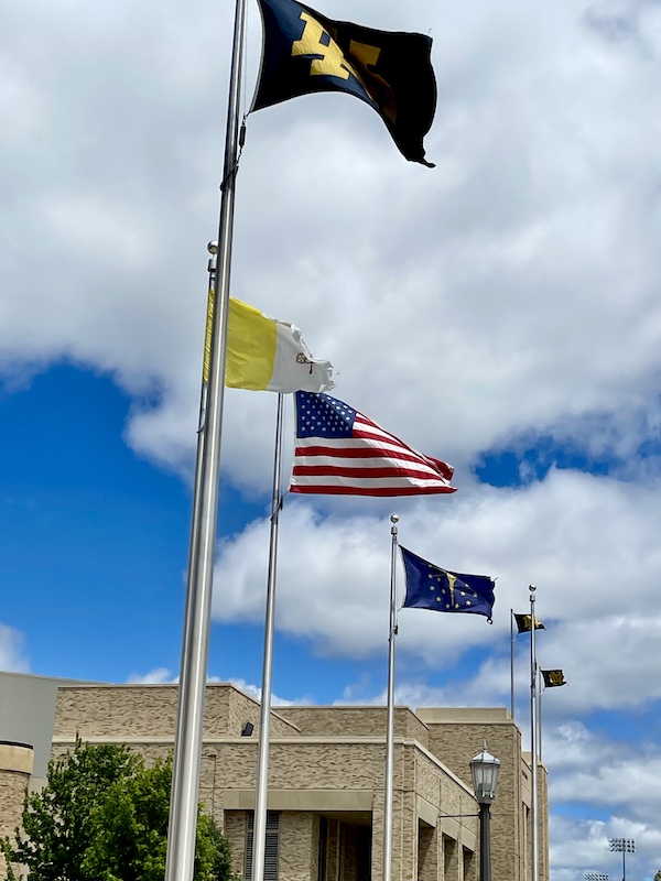 Multiple flags flying by a football stadium as we wish you a Happy July 4th 2024!