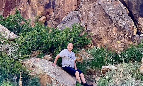 Steve resting on a low boulder with petroglyphs behind him at Petroglyphs of Parowan Gap Utah
