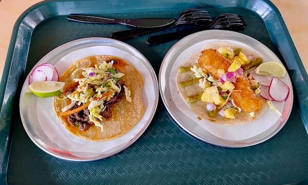Dark teal cafeteria tray topped with 2 tacos from Trejo's Tacos Hecho en Los Angeles