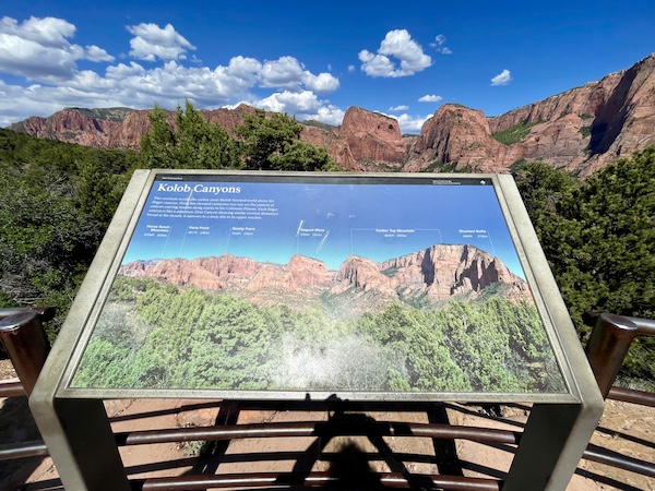 Sign for Zion National Park Kolob Canyons with red rock mountains in background