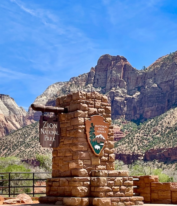 Stone pillar welcoming you to Zion National Park Utah with mountains in background