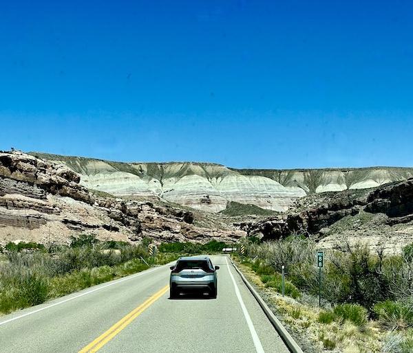 Rock formations and greenery in a rainbow of colors as a car drives through the park.