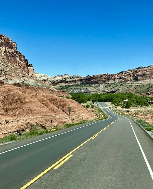 Rock formations that look like fabric folds with highway winding through Capitol Reef National Park