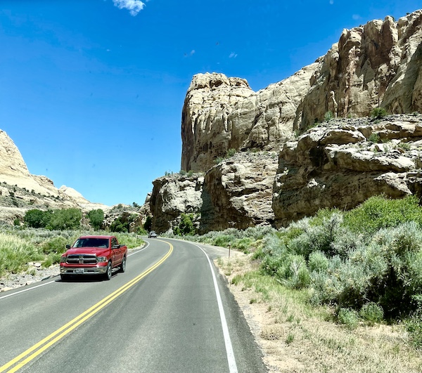 Rugged gray and white stone mountains with highway and red pickup truck at Capitol Reef National Park