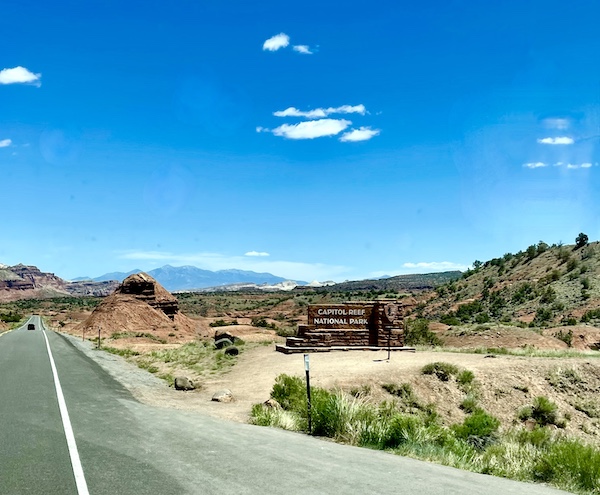 Highway though desert and mountains with sign for Capitol Reef National Park