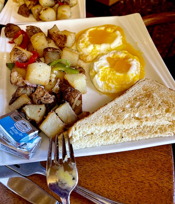 White square plate topped with 2 poached eggs, home fries and toast at Diamond Belle Saloon Durango