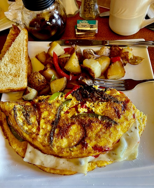 White square plate topped with a cheese omelet, bacon, home fries and toast at Diamond Belle Saloon Durango
