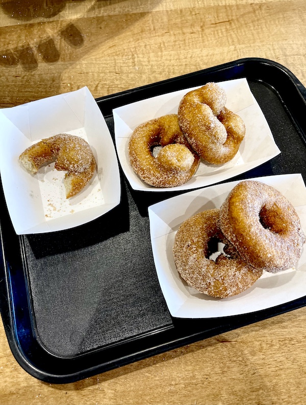 Three paper dishes with donuts on a black tray.