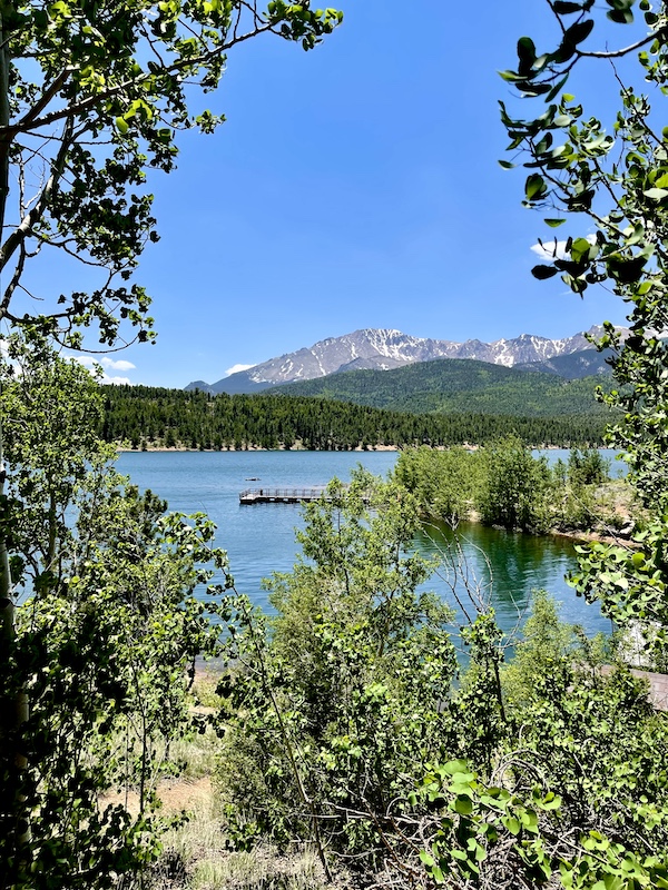 Pikes Peak in Colorado lake surrounded be lots of trees. Mountains in the background